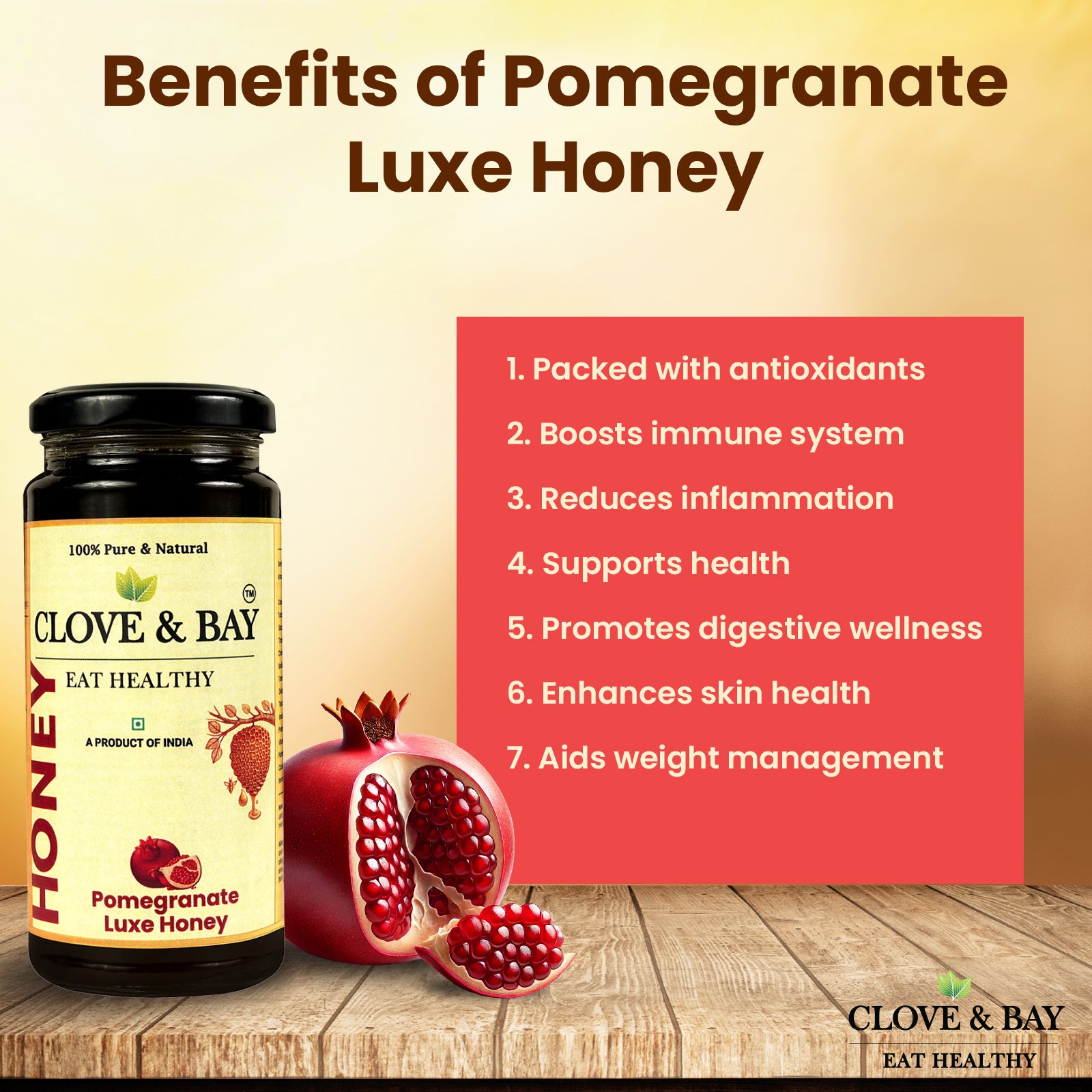 Clove & Bay Pomegranate Luxe Honey jar with pomegranate fruits and health benefits listed on a wooden surface.
